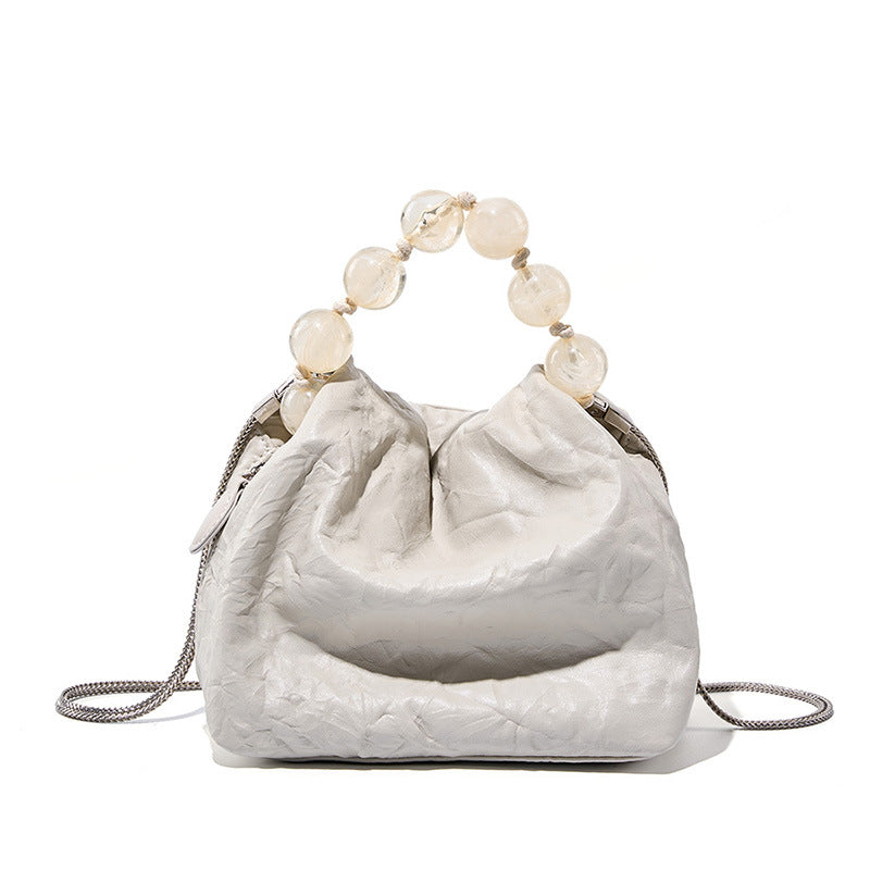 White bone colour textured small handbag with beaded handle on a white background