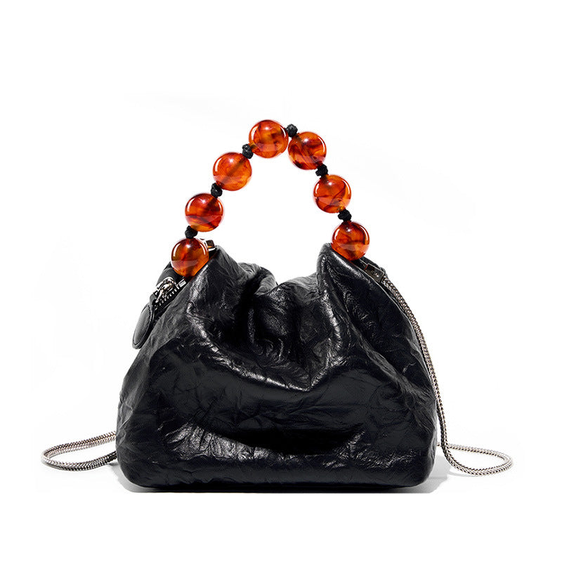 Black textured small handbag with a beaded handle on a white background. Genuine leather