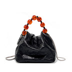 Black textured small handbag with a beaded handle on a white background. Genuine leather
