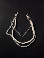 A double-layered necklace featuring a strand of white faux pearls and silver-tone chains, including a curb chain and a textured beaded chain, with lobster clasp closures at the top, displayed on a dark background.