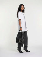 Model in a white t-shirt and baggy black jeans carrying the washed black Elsinore Buckle Belt Bag with silver bracelets and black heels