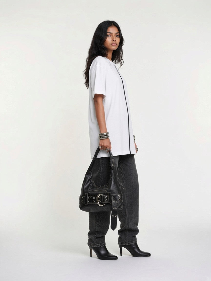 Model in a white t-shirt and baggy black jeans carrying the washed black Elsinore Buckle Belt Bag with silver bracelets and black heels