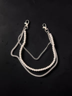 A silver-tone double-strand accessory featuring a strand of white faux pearls and a textured silver chain, laid flat on a dark background.