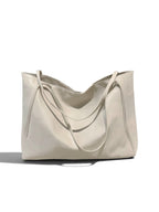 A large slouchy leather tote bag in a light cream or off-white color, featuring dual shoulder straps and a soft draped silhouette, set against a plain white background with a soft shadow.