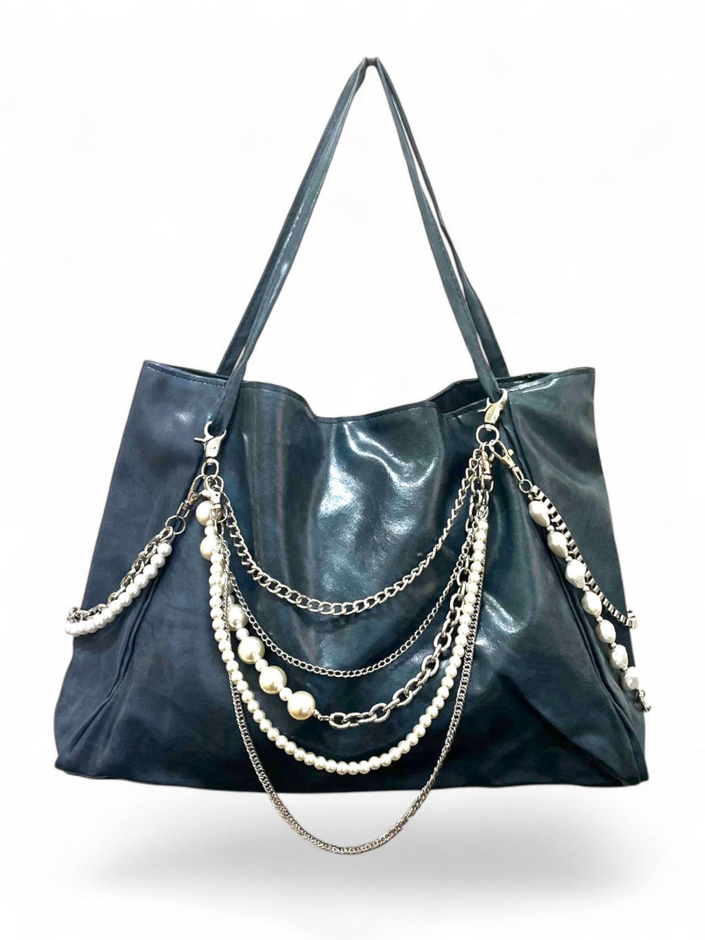 A black faux-leather hobo tote bag featuring multiple draped silver chains and strands of white faux pearls on the front, set against a plain white background.