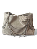 A large taupe faux-leather hobo handbag decorated with silver chains, silver links, and white faux pearls draped over the front, set against a plain white background.
