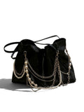 A black leather slouchy shoulder bag decorated with multiple draped silver chains and strands of white faux pearls, shown on a plain white background.